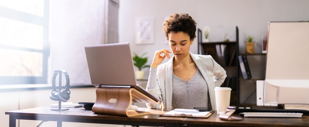 Woman Sitting at Desk Holding Her Back