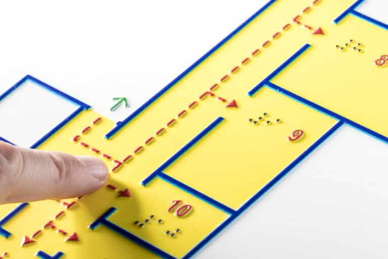 A person is pointing at a yellow floor plan that shows evacuation routes