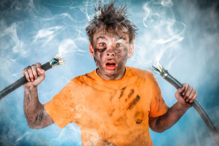 A young man holding a wire with smoke coming out of it.