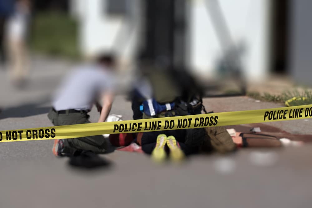 A group of people laying on the ground next to a police tape.