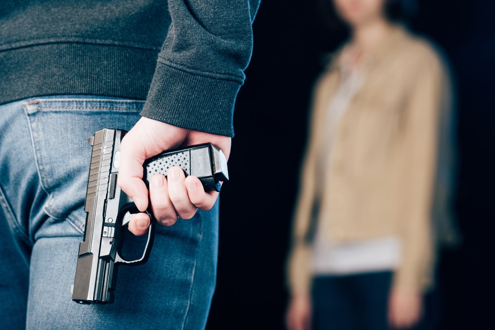 A man holding a gun in front of a woman.