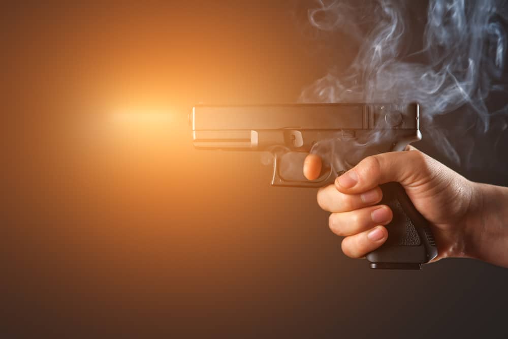 A hand holding a gun on a dark background.