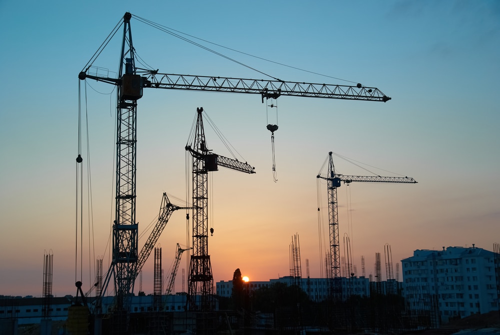 Construction cranes on a construction site at sunset.