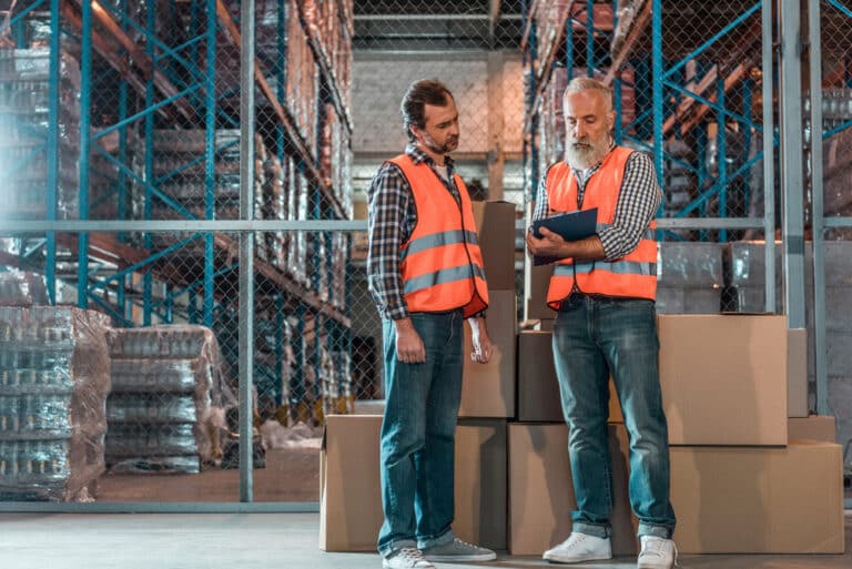 Two warehouse workers standing in a warehouse.