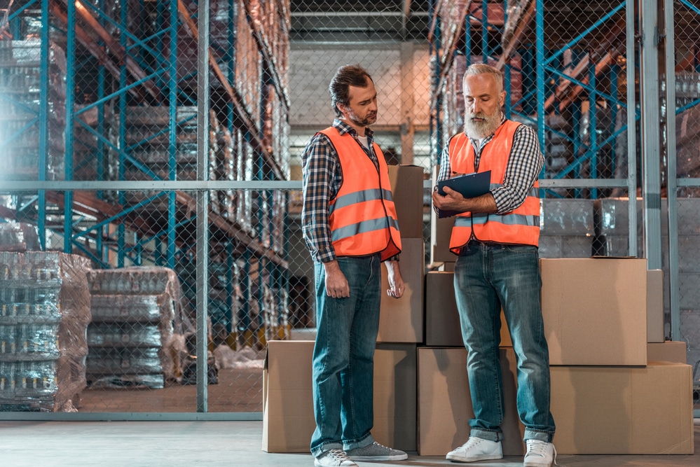 Two warehouse workers standing in a warehouse.