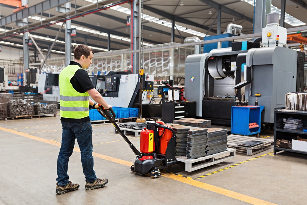 Warehouse worker using a pallet jack to move materials around a warehouse