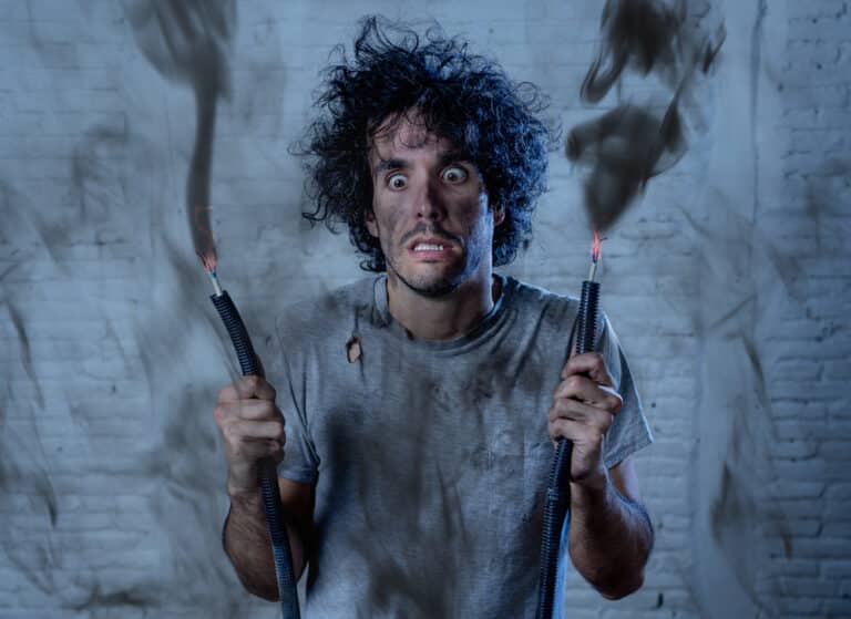 A man holding an electrical wire with smoke coming out of it.