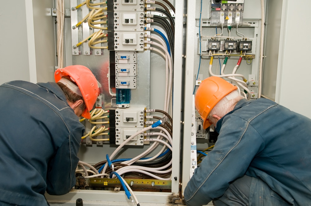 Two men working on an electrical panel.
