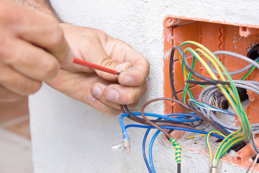 A man is putting wires into an electrical box.