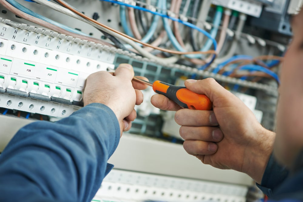 A man is working on an electrical panel.