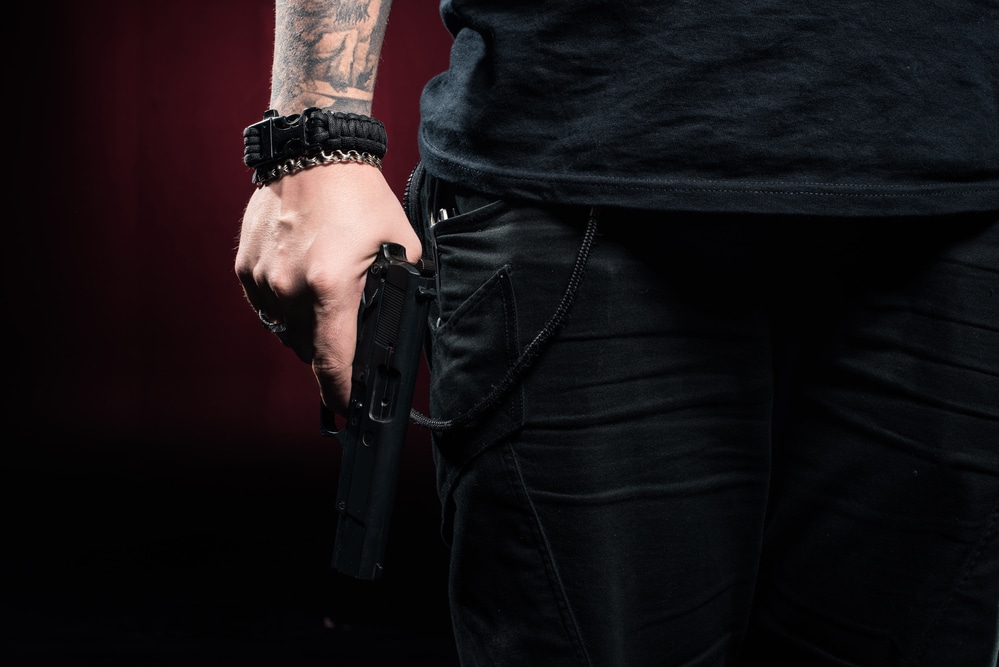 A man with tattoos holding a gun.