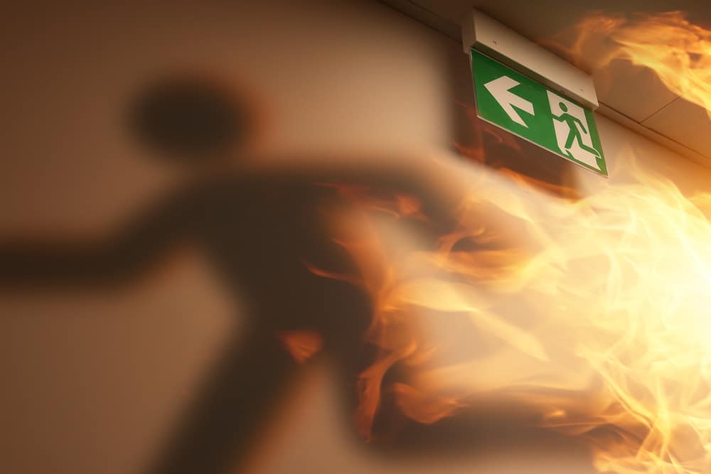 An image of a person running away from a fire exit sign.