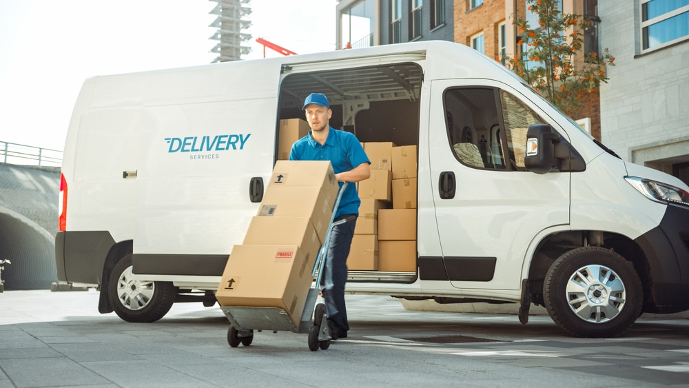 A delivery man with a box in front of a white van.