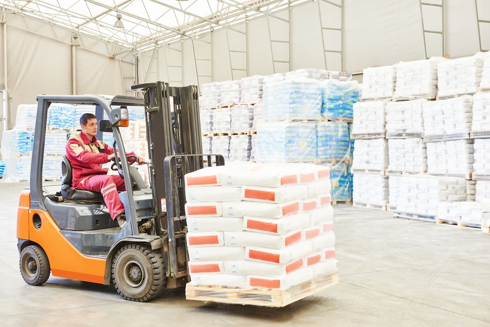 A forklift truck in a warehouse moving a pallet of materials