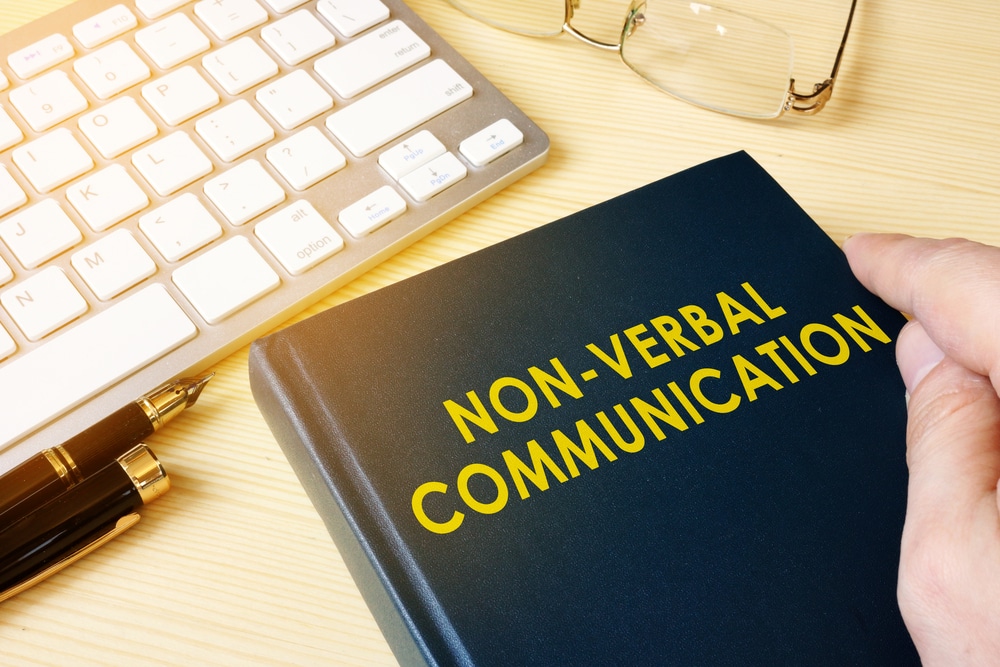 A person holding a book that says non verbal communication.