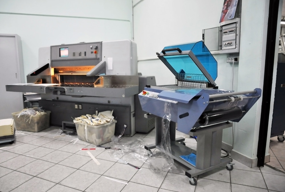 A printing press is sitting in a room with other machines.