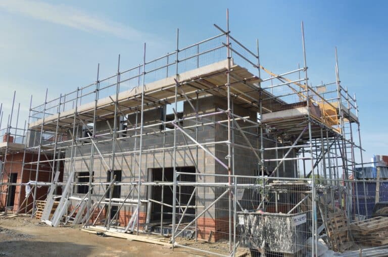 A house under construction with scaffolding surrounding the perimeter.