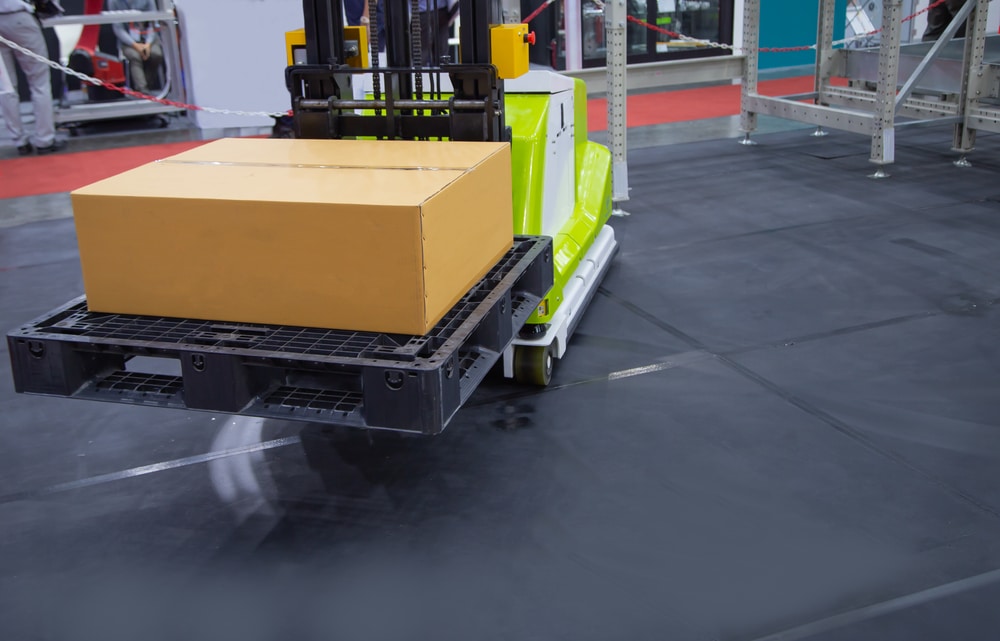 A forklift truck or straddle stacker carrying a box.
