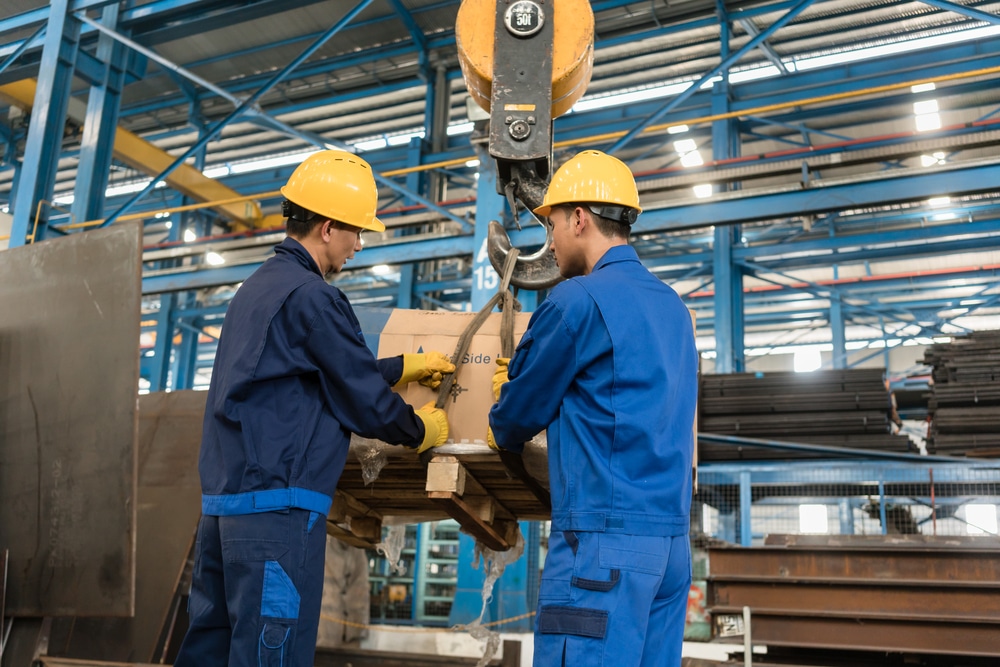 Two men working in a factory with a crane.