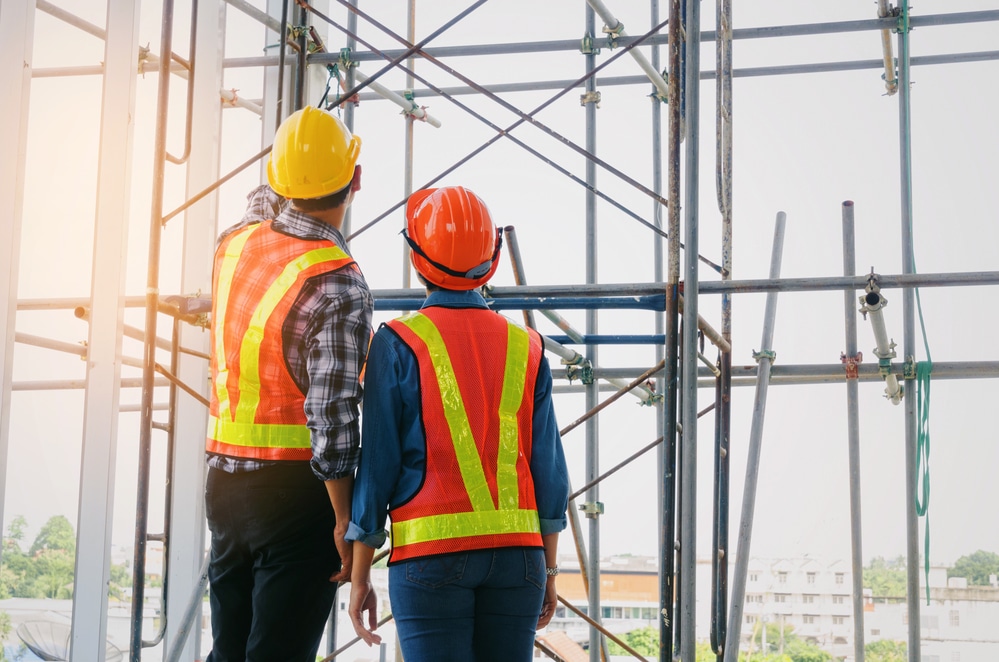 Two construction workers standing on a scaffolding.