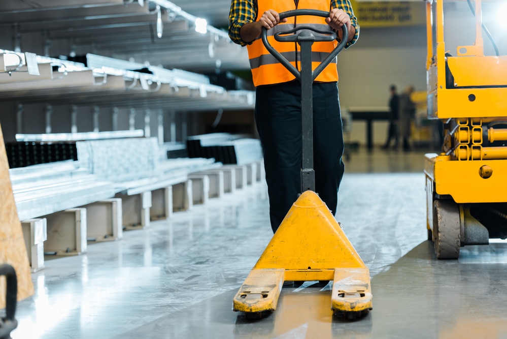 A man with a yellow forklift in a warehouse.