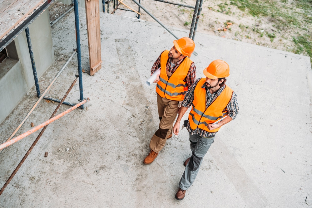 Two construction workers standing on a construction site.