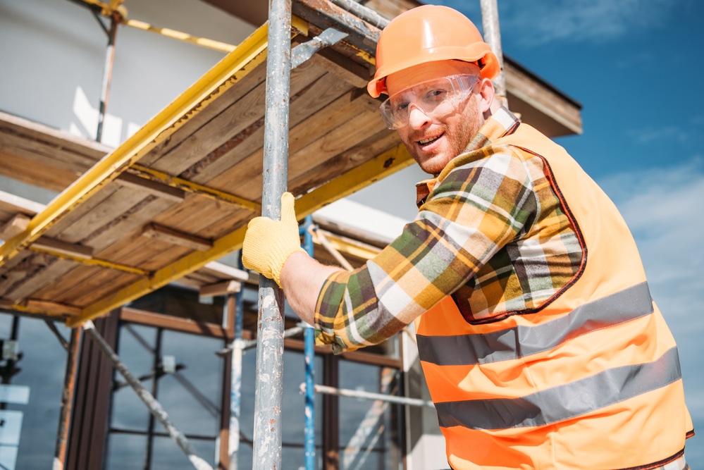 A construction worker is standing on a scaffolding.