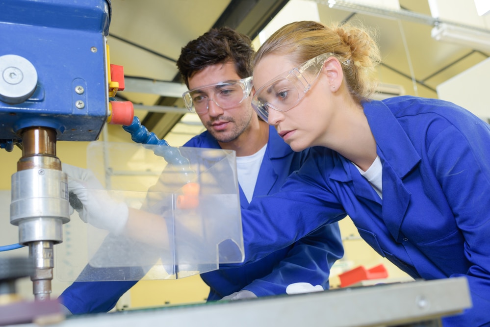 A man and a woman working on a machine.